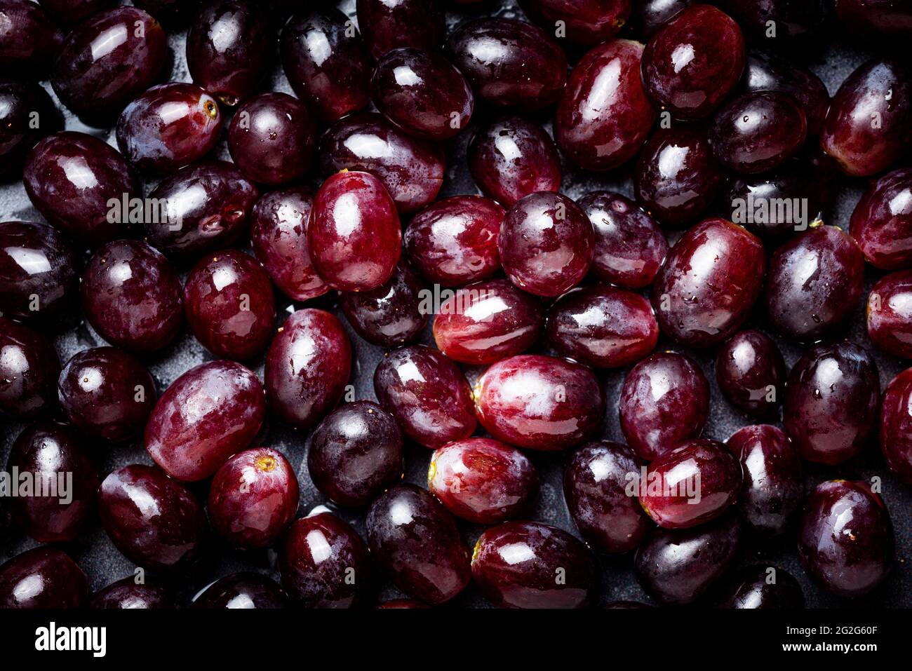 Sfondo di uve rosse ricoperte di gocce d'acqua. Foto Stock