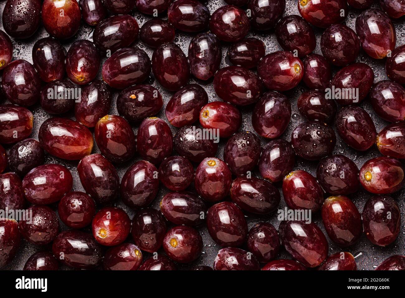 Sfondo di uve rosse ricoperte di gocce d'acqua. Foto Stock