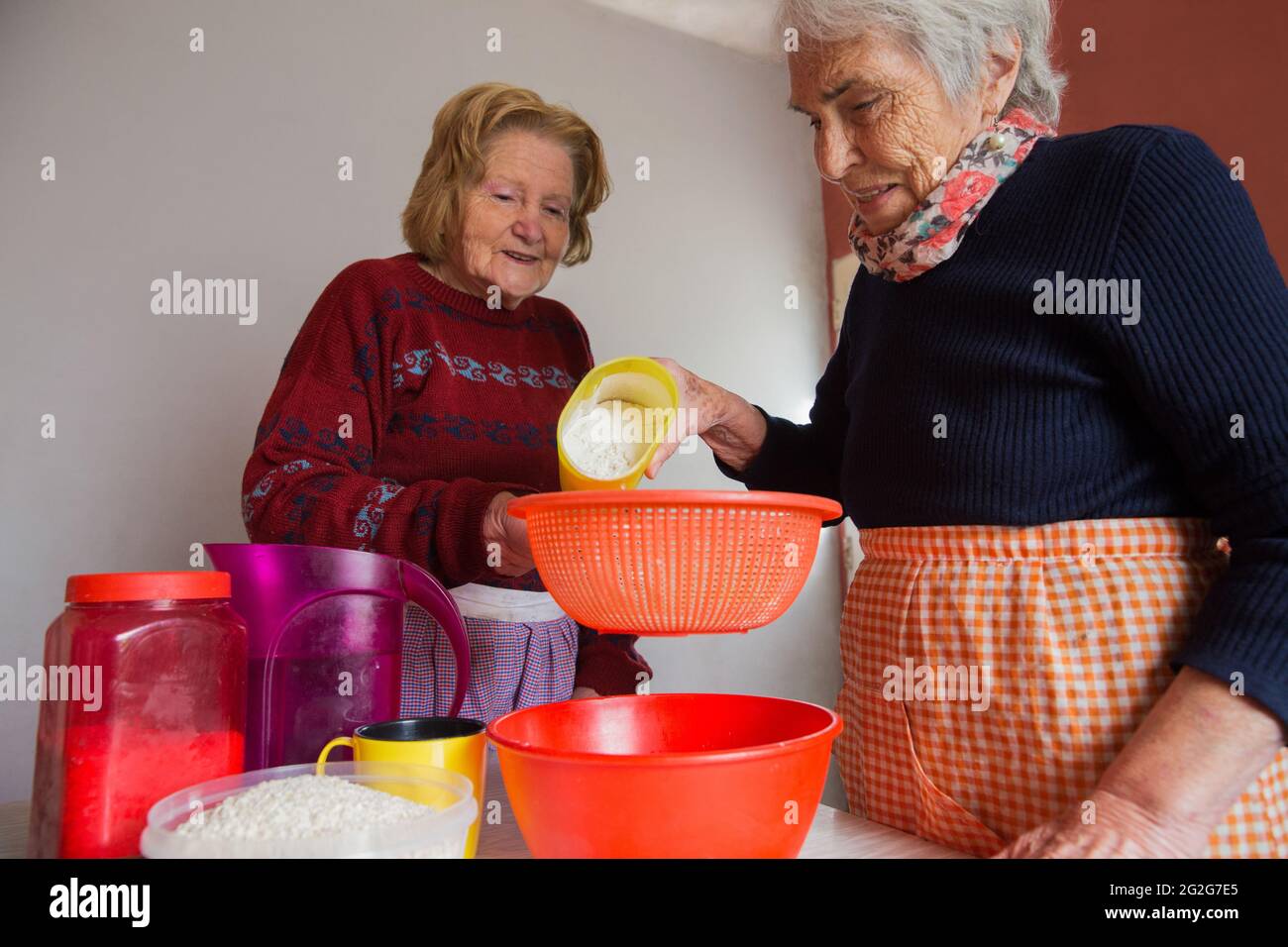 Lavoro di squadra di due sorelle anziane che cucinano cibi fatti a mano con la farina. Foto Stock