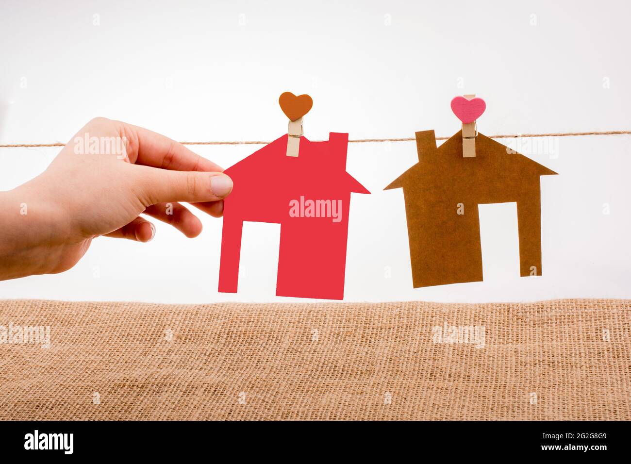 Mano che tiene una casa di carta su tela Foto Stock