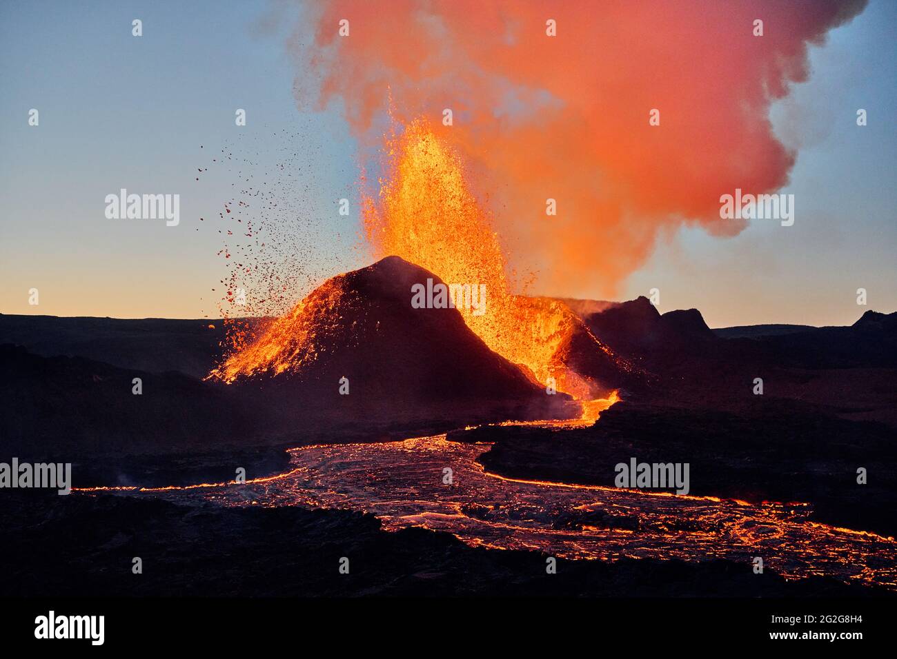 Lava calda che eruttava dal vulcano al tramonto Foto Stock