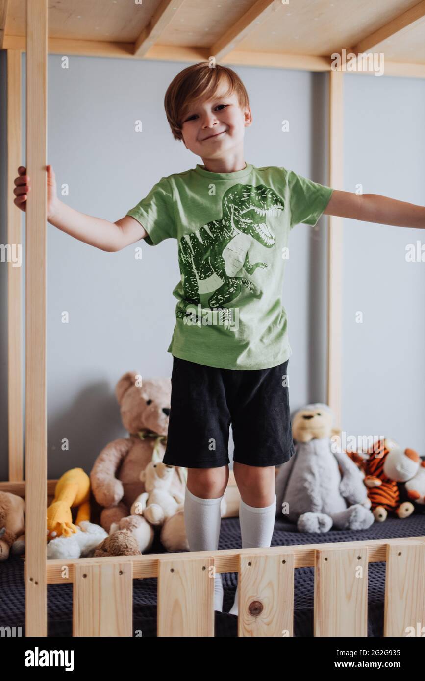 ragazzo di 5 anni che gioca in camera, indossa una t-shirt verde con stampa dinosaurus Foto Stock