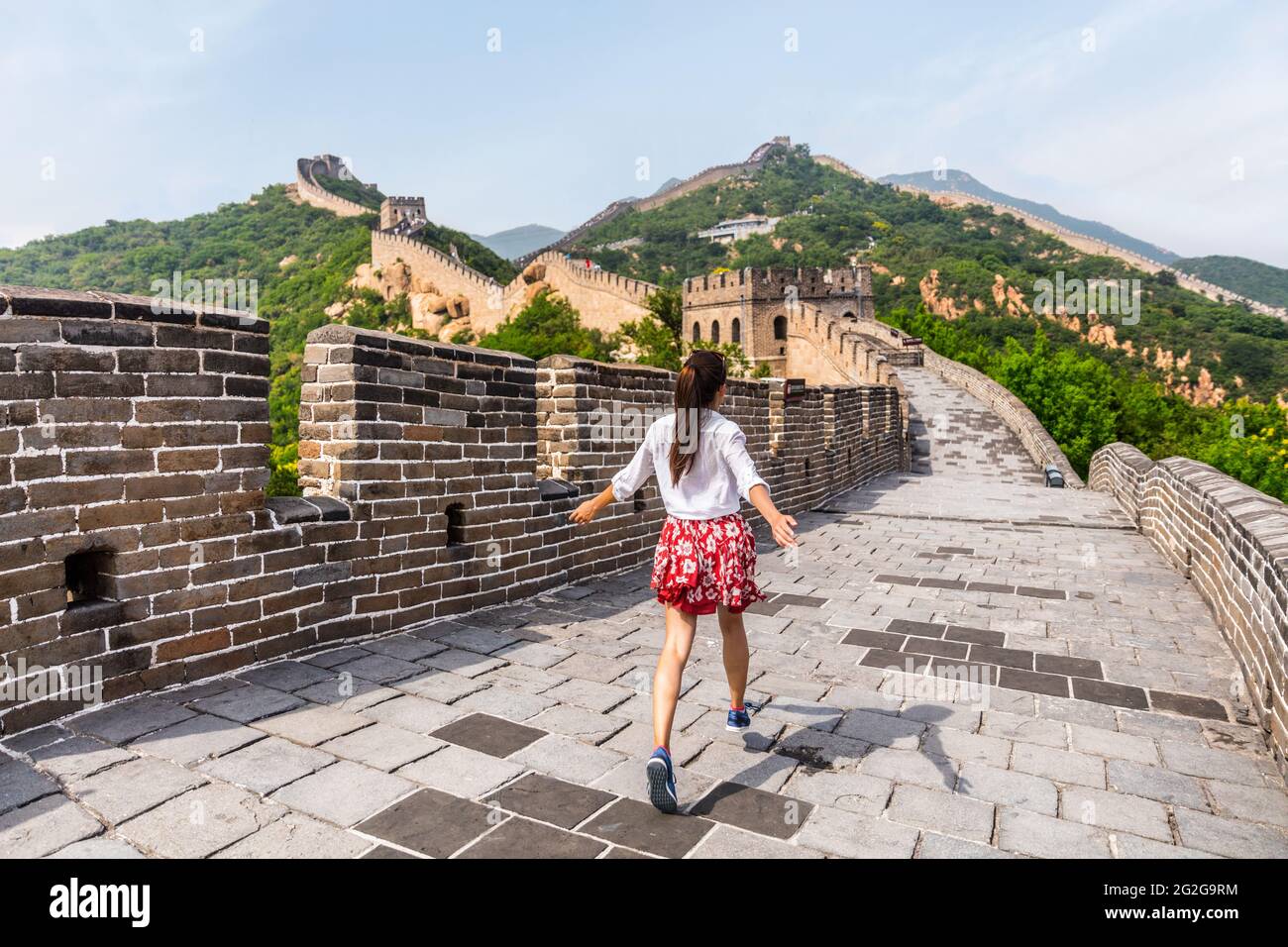 Felice allegra gioiosa turista donna alla Grande Muraglia della cina divertirsi in viaggio sorridendo ridere e ballare durante il viaggio di vacanza in Asia. Ragazza Foto Stock