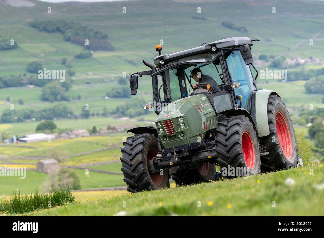 Pascoli con un'altura, con un trattore Hurlimann e un topper Fleming, che lo liberano dai vampate. North Yorkshire, Regno Unito. Foto Stock