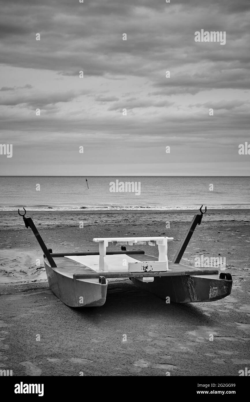 Spiaggia desolata con barca di salvataggio vicino al mare. Rimini, Italia. Fotografia in bianco e nero, paesaggio Foto Stock