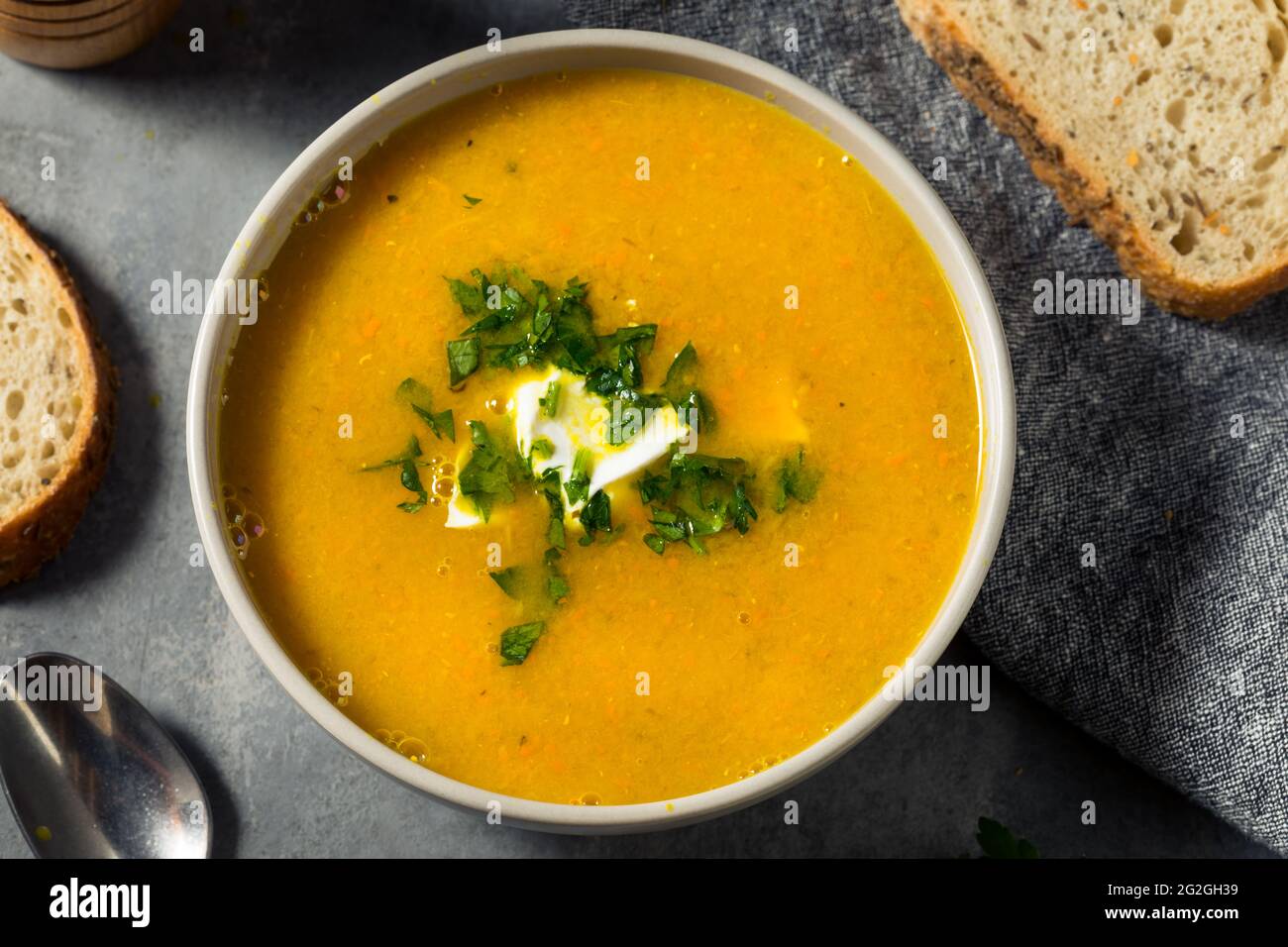 Zuppa di lenticchie di carota sana fatta in casa con prezzemolo e panna acida Foto Stock