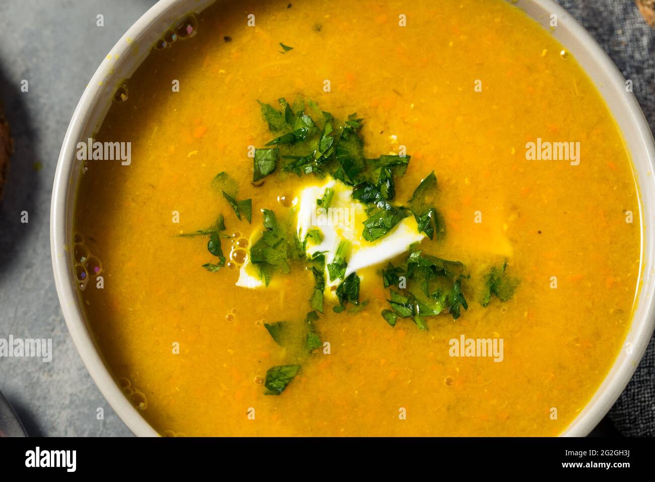 Zuppa di lenticchie di carota sana fatta in casa con prezzemolo e panna acida Foto Stock