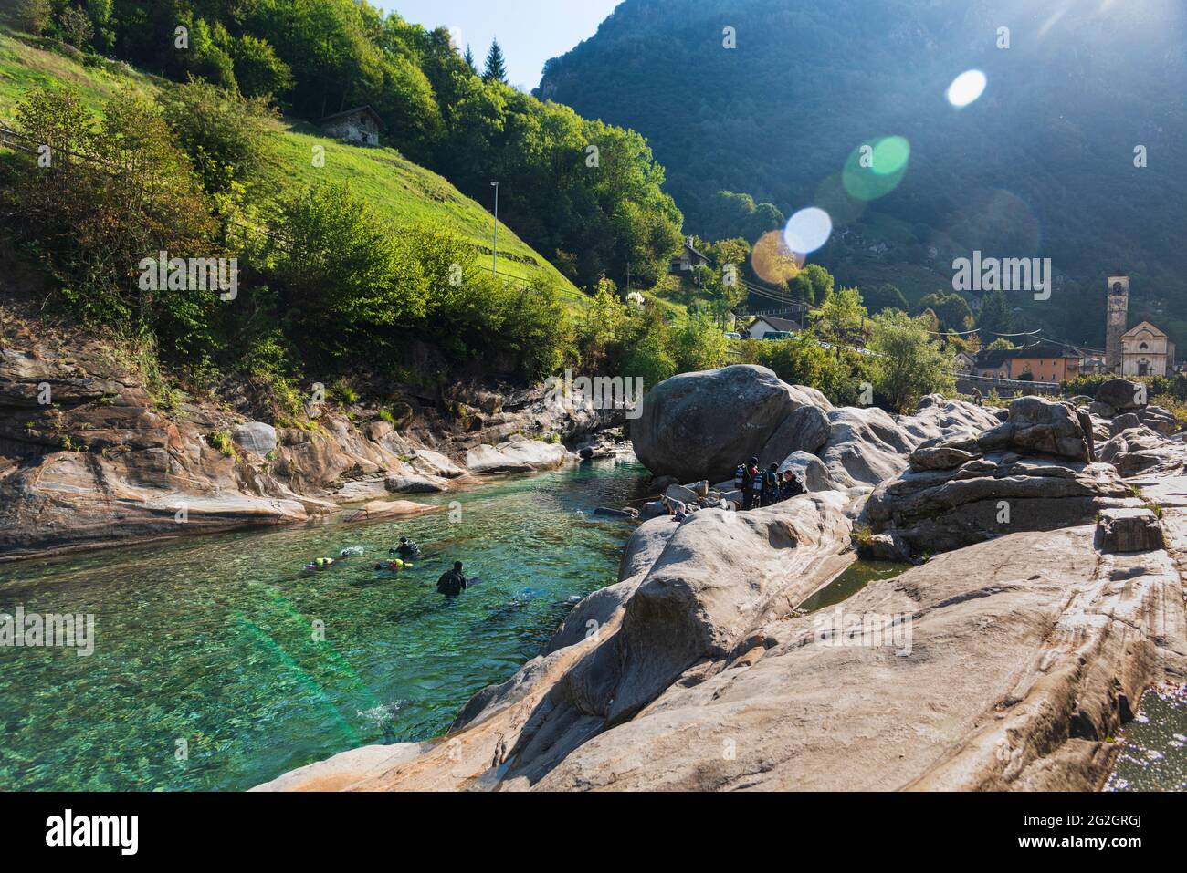 Svizzera, Ticino, Val Verzasca, Verzasca, tuffatori nel fiume presso il popolare bacino con le rocce granitiche. Svasatura lente. Foto Stock
