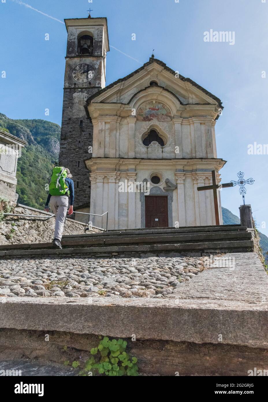 Impressioni da Lavertezzo in Val Verzasca, Locarno, Canton Ticino in Svizzera: Meta turistica molto apprezzata per escursioni, immersioni e nuoto. Donna con zaino sale le scale fino alla chiesa settecentesca di Santa Maria degli Angeli. Foto Stock