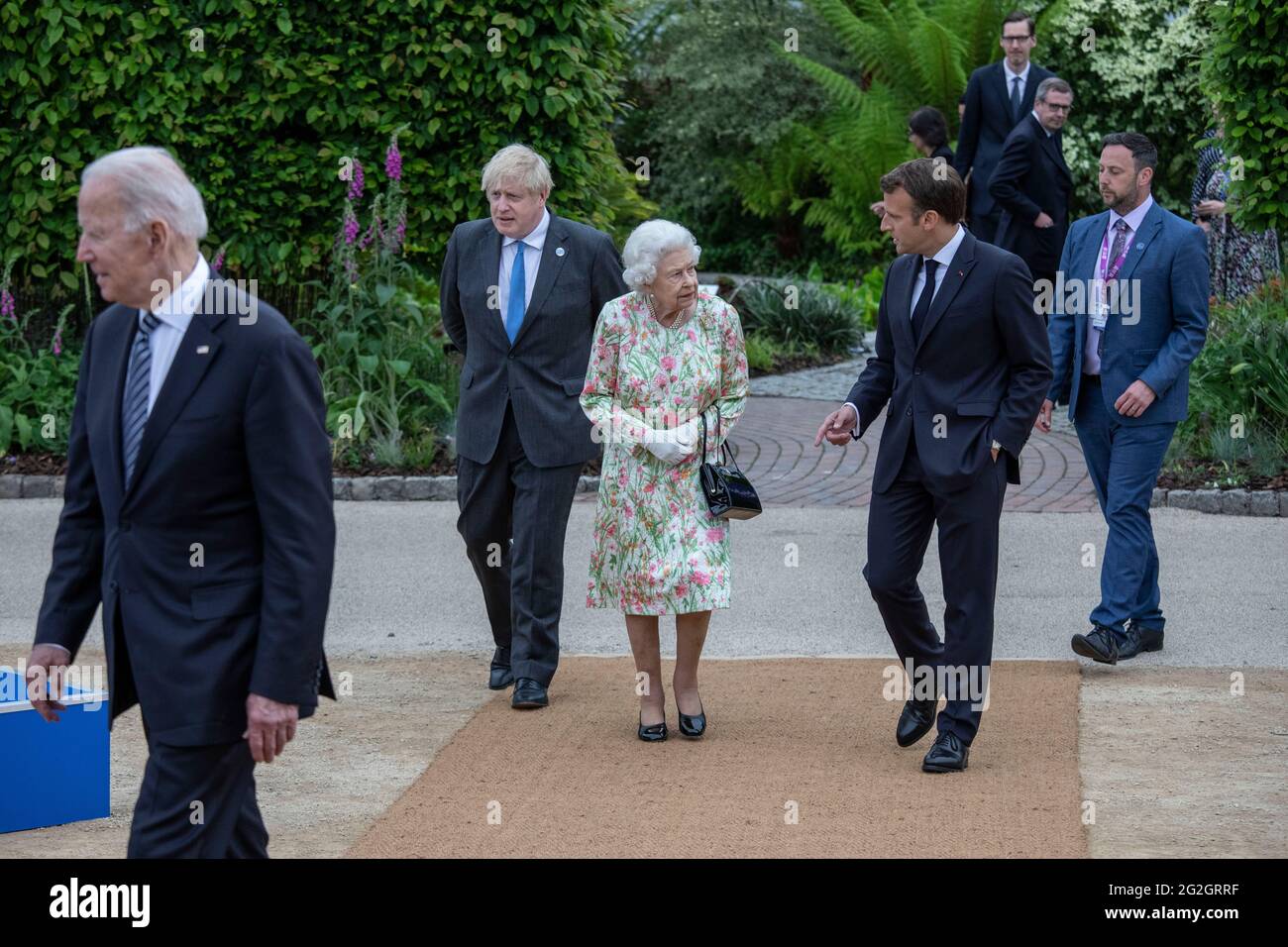 La regina Elisabetta II, parlando con il presidente francese Emmanuel Macron come il primo ministro britannico Boris Johnson guarda sopra, mentre si fanno strada per una foto di gruppo prima di un ricevimento al progetto Eden durante il vertice del G7 in Cornovaglia. Data immagine: Venerdì 11 giugno 2021. Foto Stock