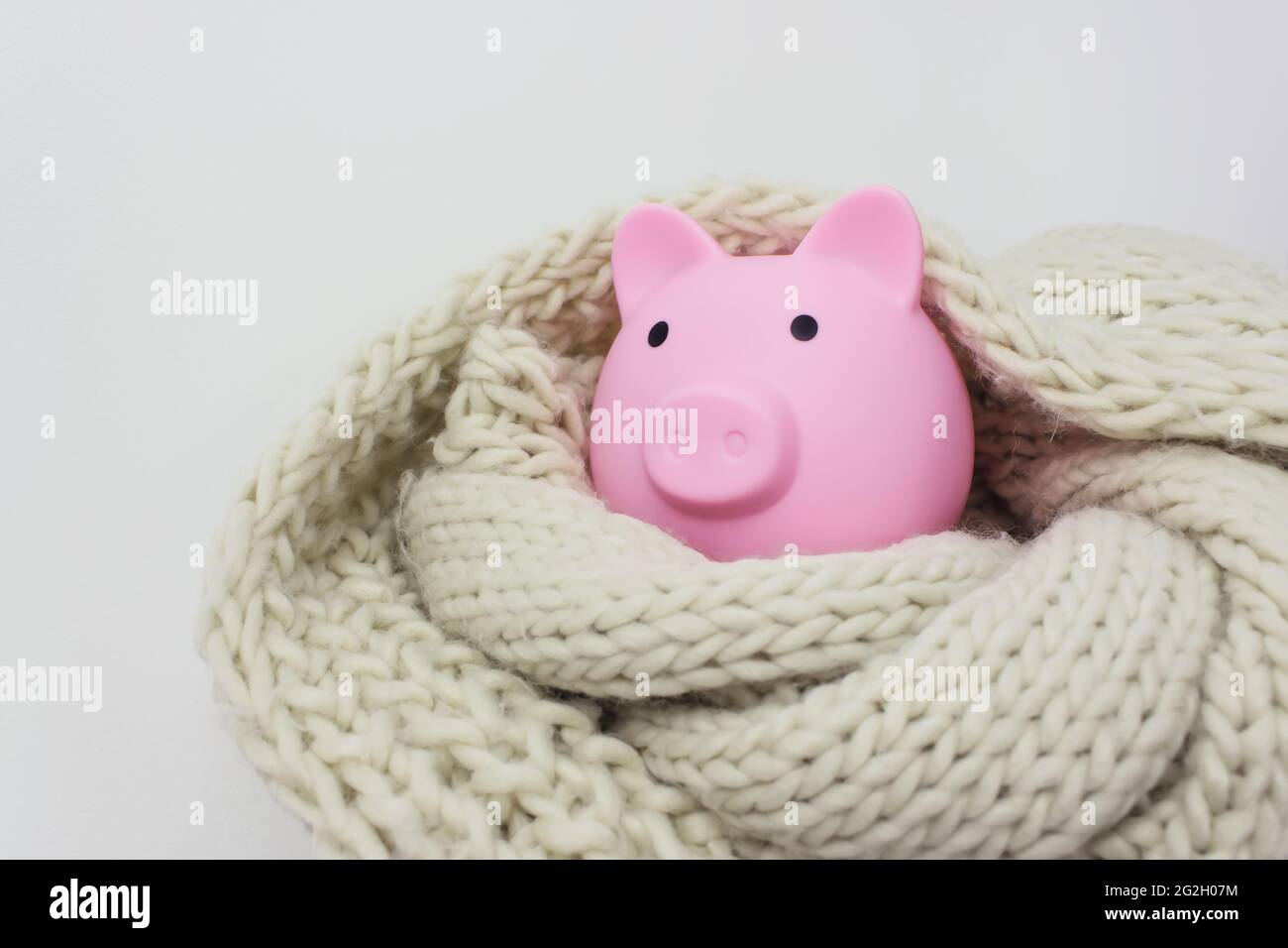 Banco di porcellini e sciarpa a maglia. Concetto di risparmio energetico. Concetto di pagare per il riscaldamento a casa Foto Stock