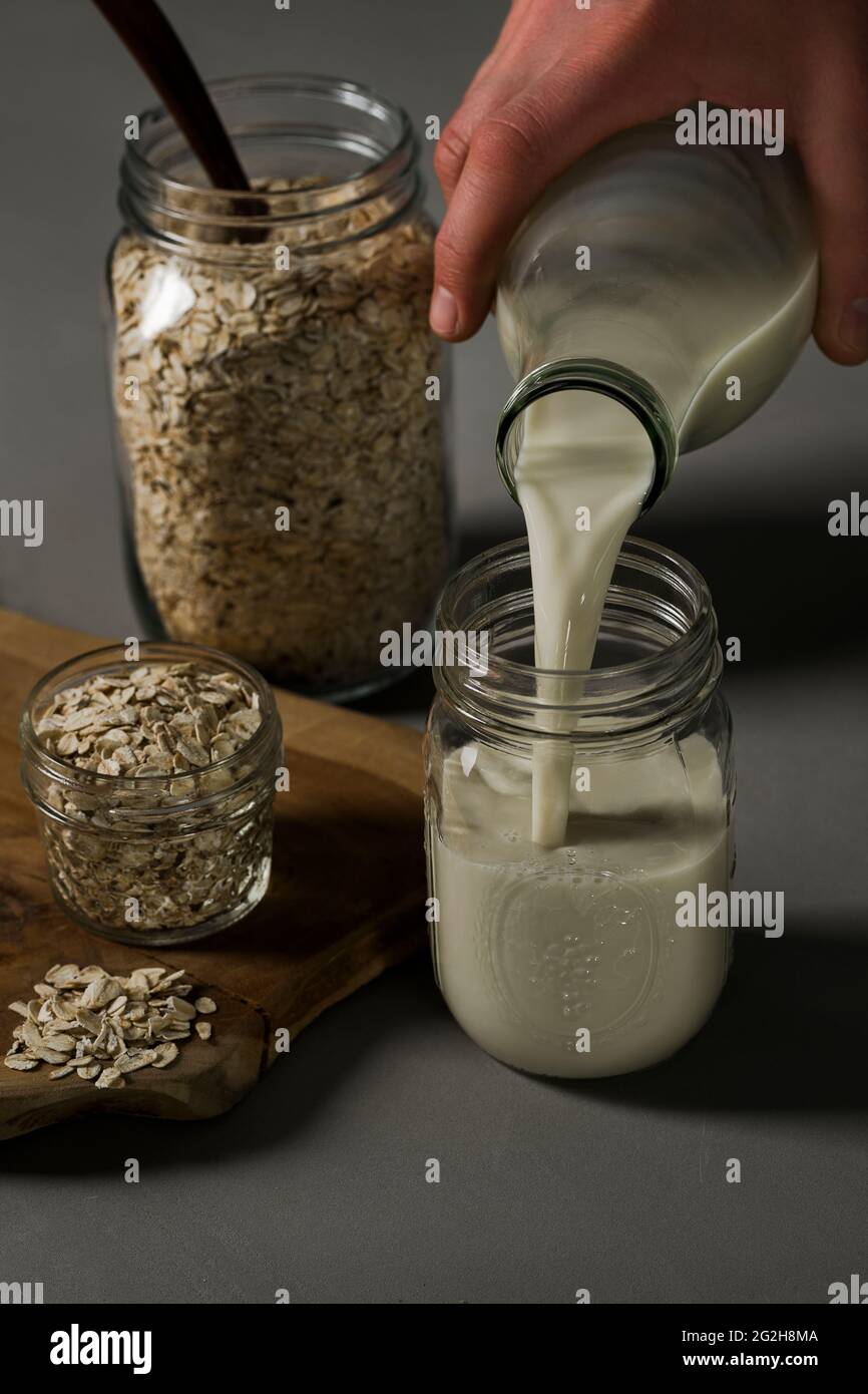 Latte d'avena, versare, vasetto di muratore, cucchiaio, tavola, farinata d'avena Foto Stock