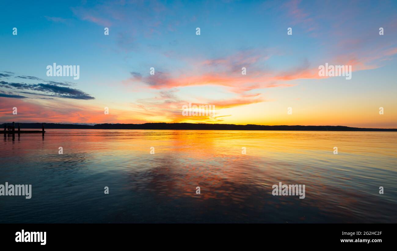 Il sole tramonta su Puget Sound nello stato occidentale di Washington creando uno sfondo di forme rosa e arancione nel cielo serale. Foto Stock