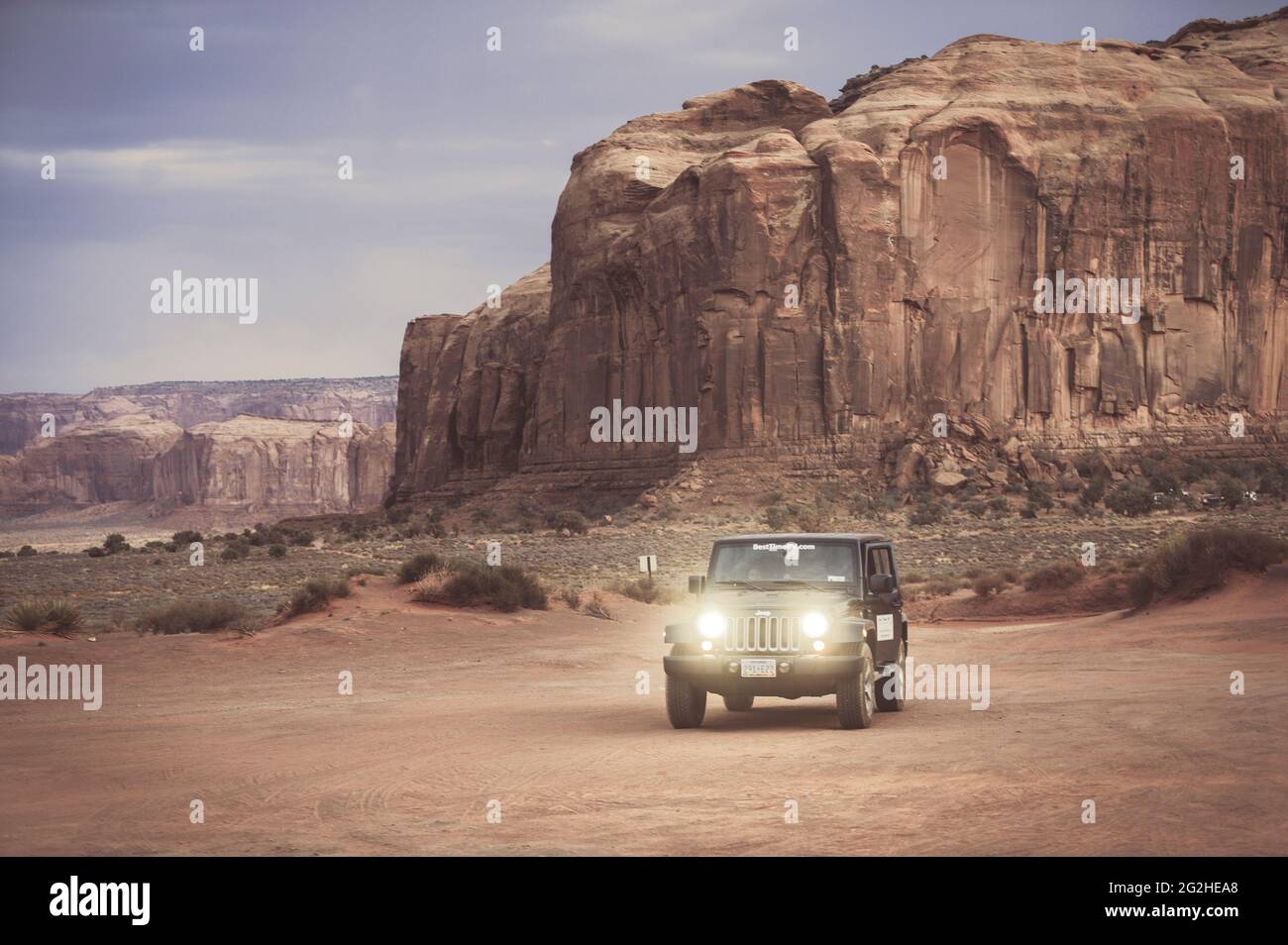Jeep Wrangler di fronte al Thumb. Il paesaggio unico di Monument Valley, Utah, USA al tramonto in serata. Foto Stock