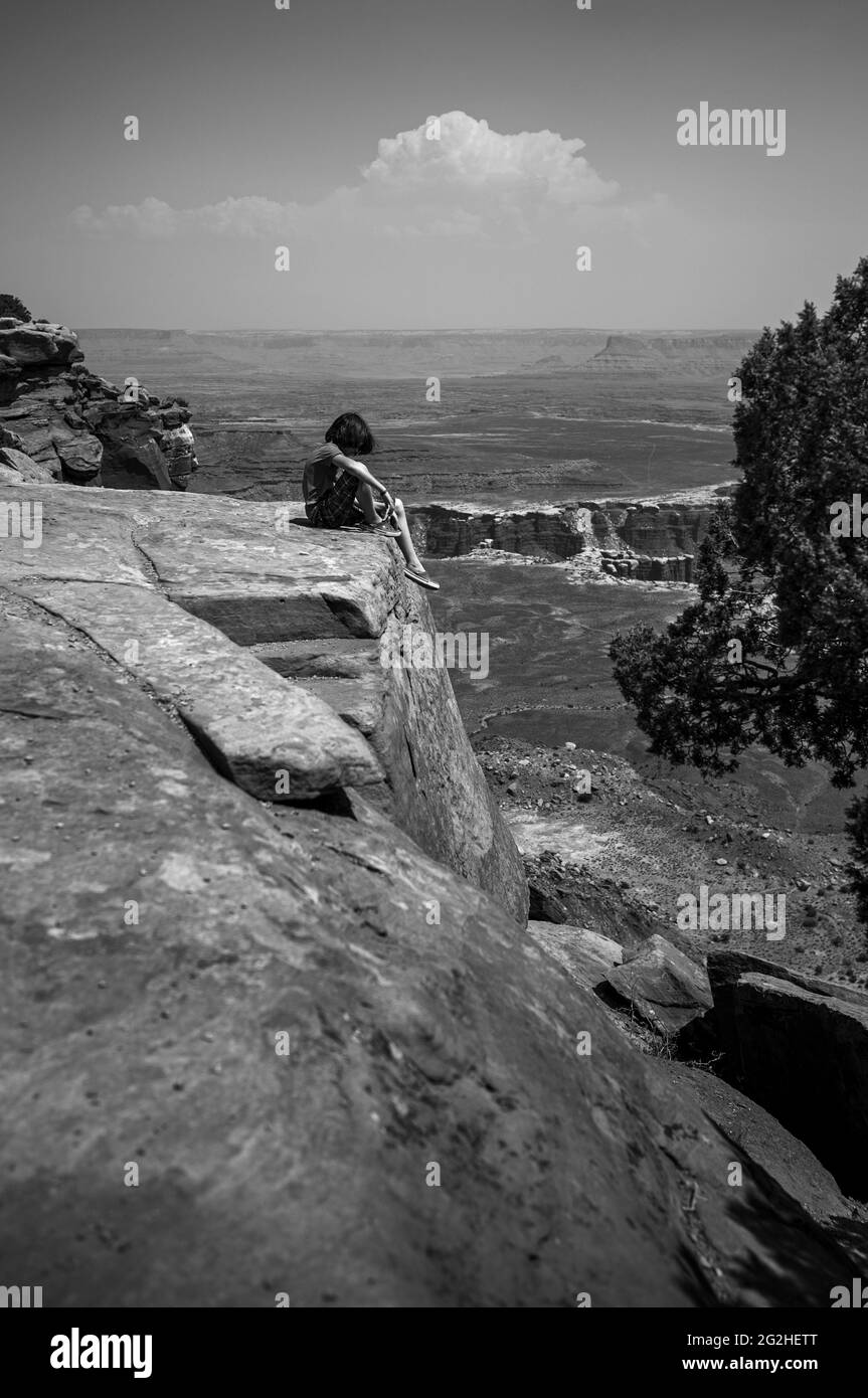 Boy on a Cliff on Grand View Point. Escursione panoramica e facile a 2 km circa lungo il bordo della mesa con ampie vedute del suggestivo terreno del canyon nel Canyonlands National Park, Utah, USA Foto Stock