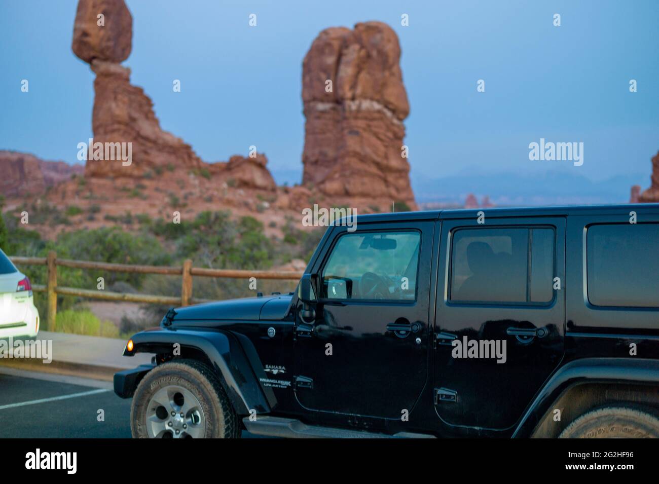 Wrangler Jeep al parcheggio presso la Balanced Rock - una massiccia roccia che riposa su una stretta colonna nel Parco Nazionale di Arches, vicino a Moab nello Utah, USA Foto Stock