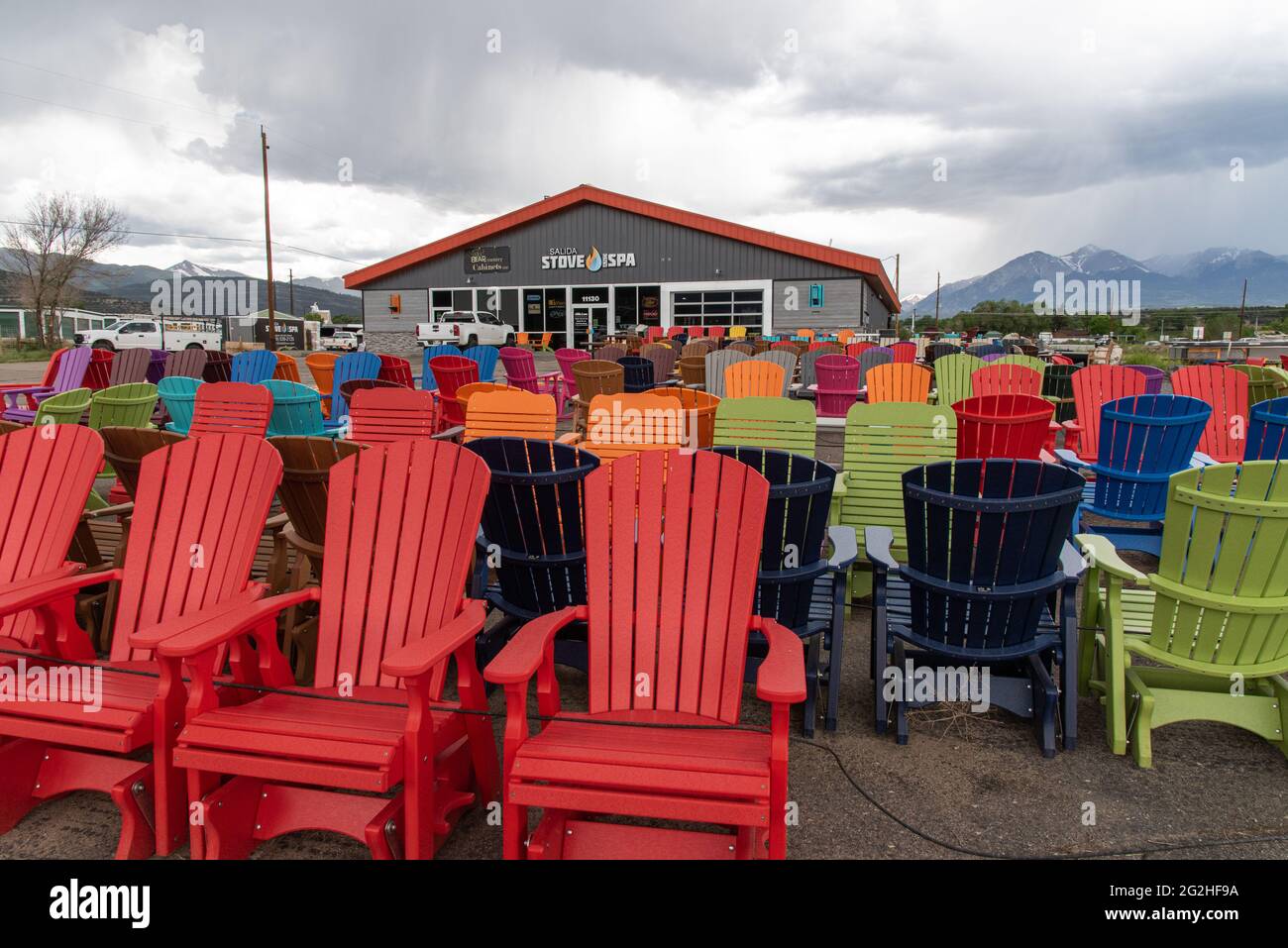 Sedie da prato dai colori vivaci all'aperto di fronte a un negozio di ferramenta in Colorado in una giornata torbida e nuvolosa. Foto Stock