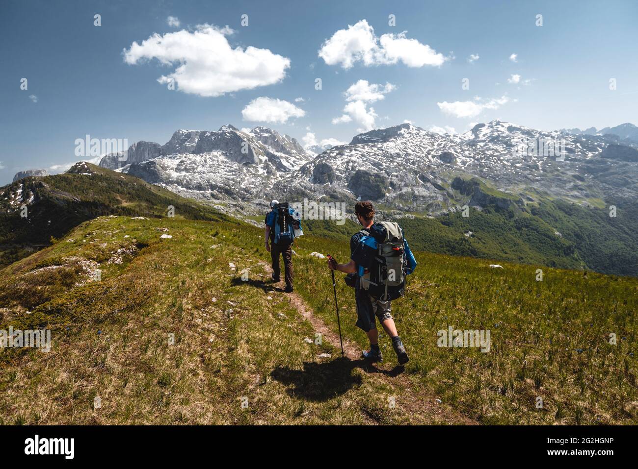 La vista segue due escursionisti da vicino su un sentiero battuto verso le montagne del Parco Nazionale di Prokletije Foto Stock