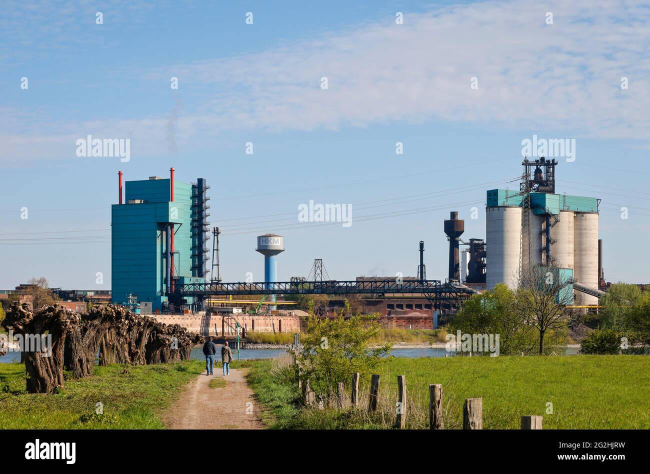 Duisburg, Renania Settentrionale-Vestfalia, Germania - paesaggio industriale nella zona della Ruhr, passeggini a piedi sul Reno di fronte allo sfondo industriale di HKM Huettenwerke Krupp Mannesmann. Foto Stock