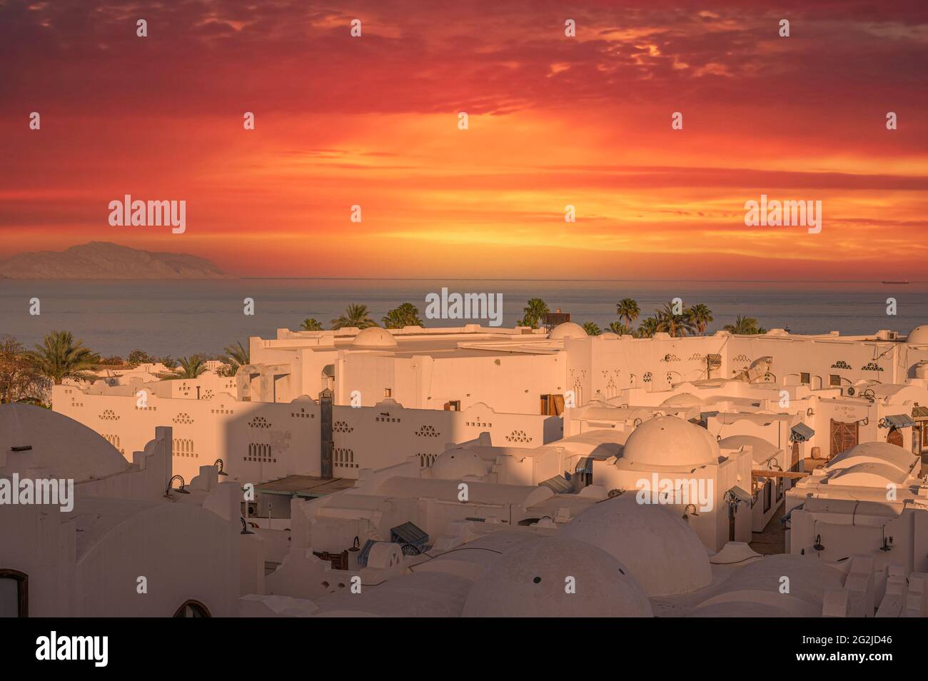 favolosa e misteriosa città araba bianca sotto il suggestivo tramonto del cielo rosso. Vista aerea. Tetti e cupole di un'antica città araba al tramonto Foto Stock