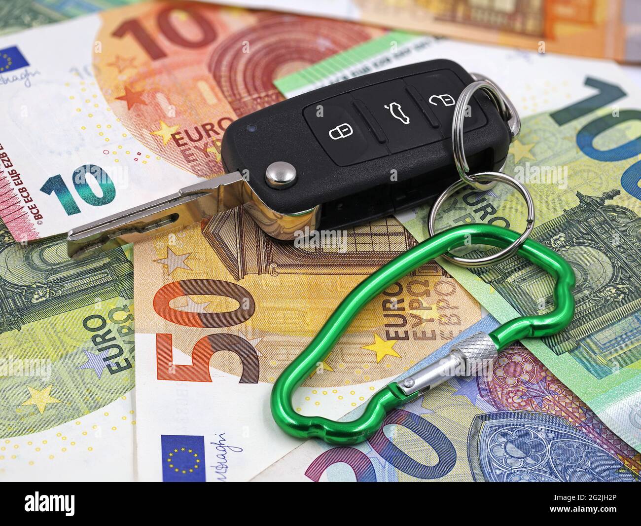 chiave auto con moschettone a forma di automobile su fondo di soldi dell'euro, concetto di assicurazione dell'automobile Foto Stock