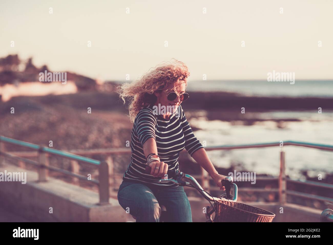 Giovane donna godere di giro in bicicletta e sorriso in attività di svago all'aperto - le donne caucasiche hanno divertimento da sole - mare oceano in background - concetto di stile di vita sano Foto Stock