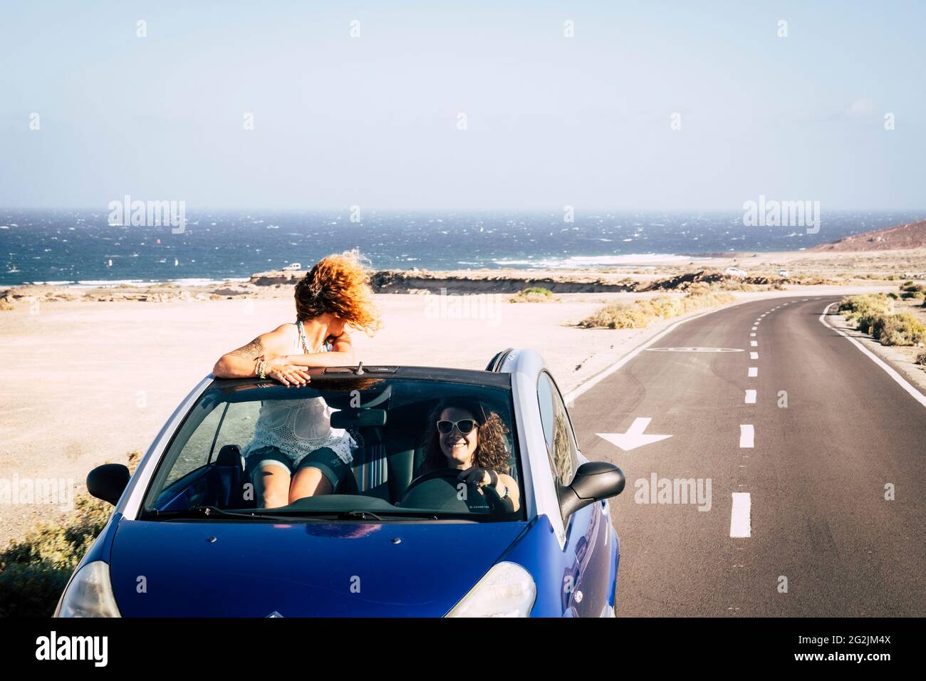 Auto viaggio amici trasporto due felice donna ejoy convertibile auto insieme in estate viaggio vacanza - mare e spiaggia in background - guida e avendo concetto di divertimento Foto Stock