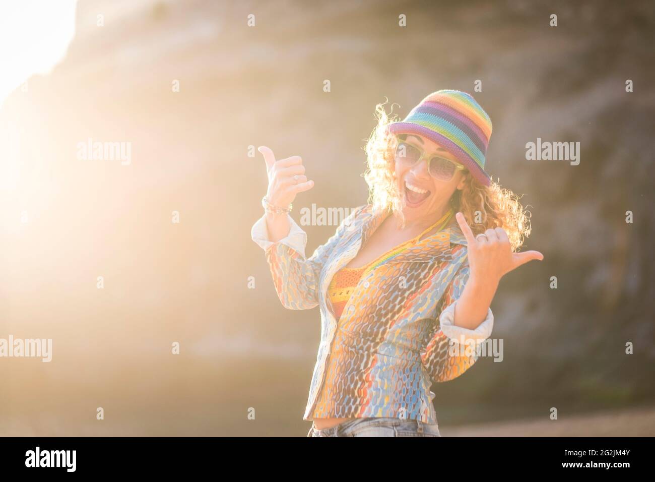 Allegro ritratto di donna adulta in attività di svago all'aperto divertente da solo guardando e sorridendo alla macchina fotografica - giovani donne e stile di vita felice con abiti colorati e cappello godere Foto Stock