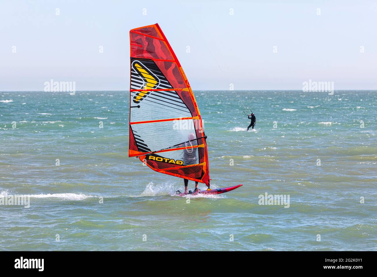 Un uomo Wind Surf sulla Manica con un Kite surfer in lontananza vicino Hythe, Kent, UK Foto Stock