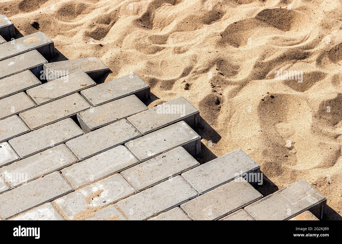 Posa di lastre per pavimentazione in calcestruzzo su fondazioni sabbiose Foto Stock
