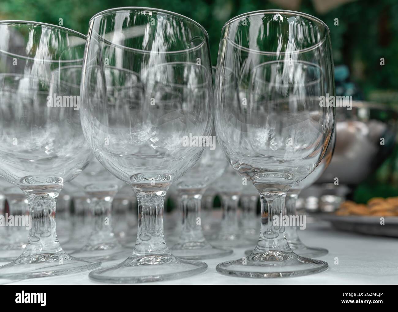 Bicchieri da vino trasparenti in vetro vuoti su un tavolo su sfondo sfocato. Bicchieri da vino in fila. Messa a fuoco selettiva, primo piano. Foto Stock