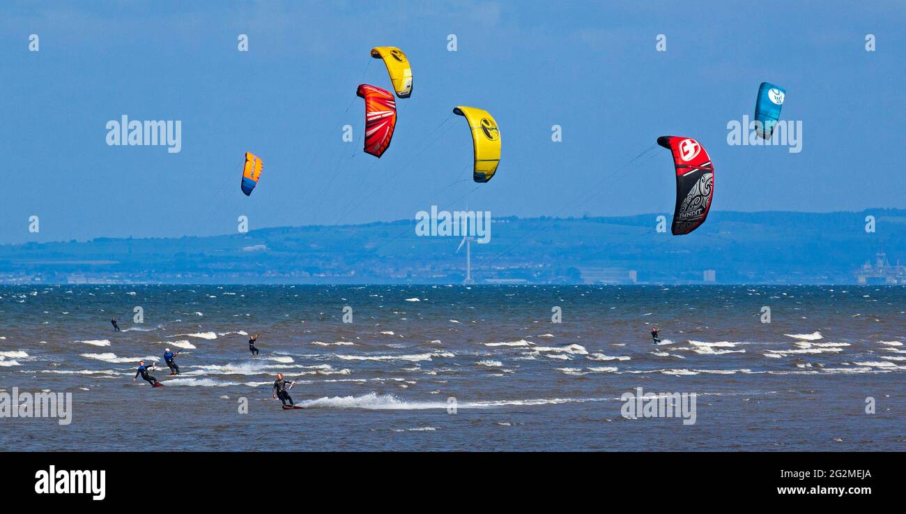 Longniddry, East Lothian, Scozia, Regno Unito. 12 giugno 2021. Vento 24 km/h potenziali raffiche 35 km/h con sole e nuvole che sembrava essere il tempo perfetto per più di 20 Kite Surfers che hanno dimostrato le loro abilità sul Firth of Forth. Foto Stock