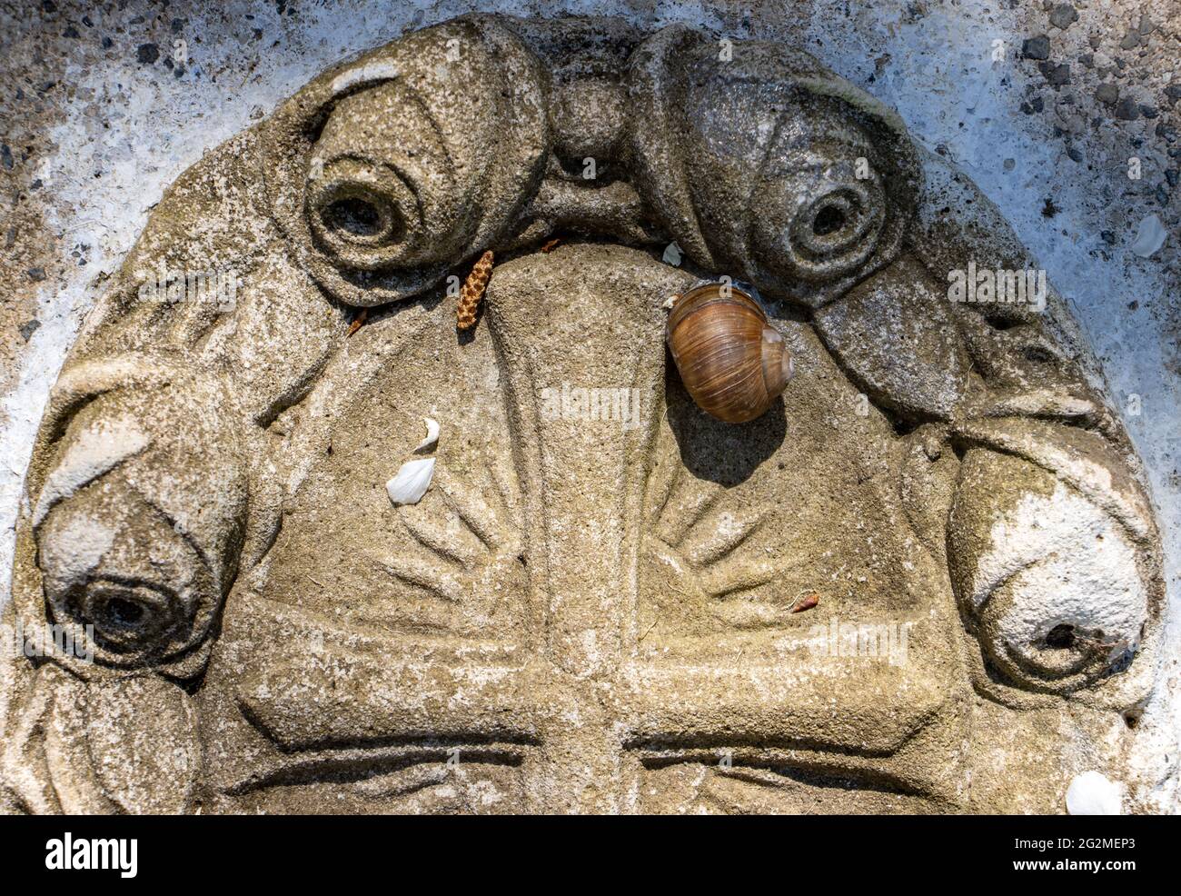 Croce cristiana su una lapide con una lumaca, primo piano. Foto Stock