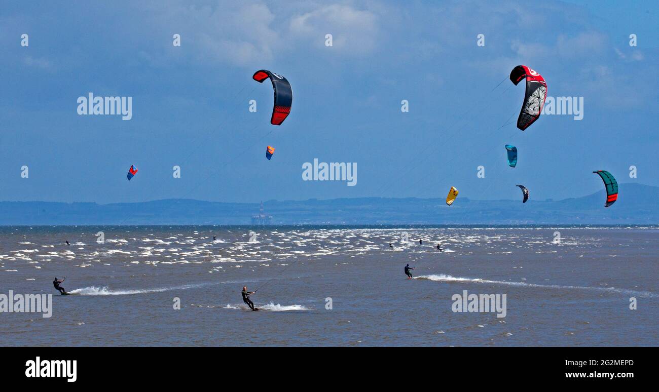Longniddry, East Lothian, Scozia, Regno Unito. 12 giugno 2021. Vento 24 km/h potenziali raffiche 35 km/h con sole e nuvole che sembrava essere il tempo perfetto per più di 20 Kite Surfers che hanno dimostrato le loro abilità sul Firth of Forth. Foto Stock