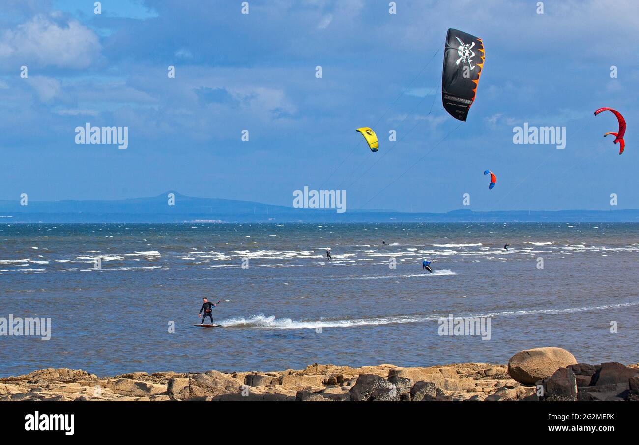 Longniddry, East Lothian, Scozia, Regno Unito. 12 giugno 2021. Vento 24 km/h potenziali raffiche 35 km/h con sole e nuvole che sembrava essere il tempo perfetto per più di 20 Kite Surfers che hanno dimostrato le loro abilità sul Firth of Forth. Foto Stock