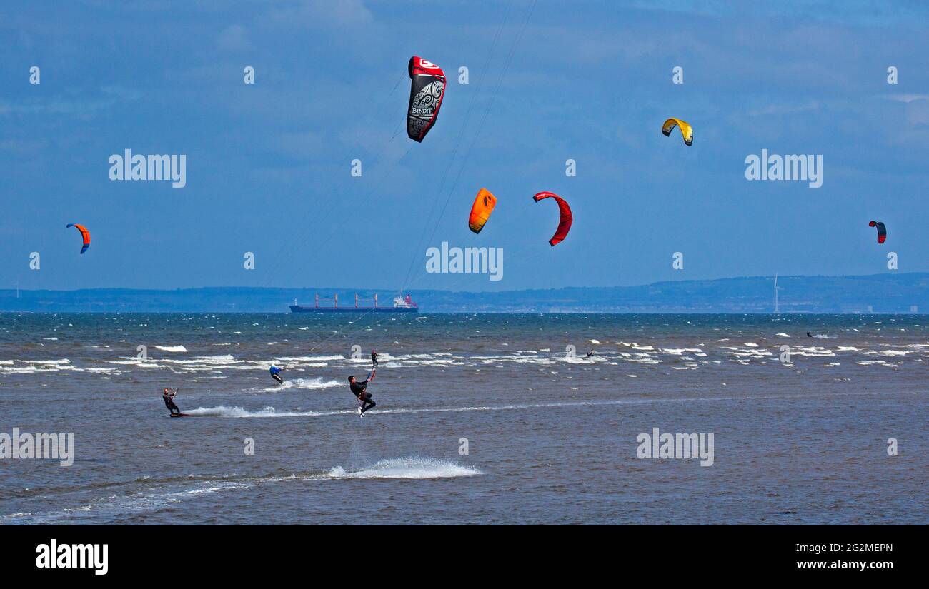 Longniddry, East Lothian, Scozia, Regno Unito. 12 giugno 2021. Vento 24 km/h potenziali raffiche 35 km/h con sole e nuvole che sembrava essere il tempo perfetto per più di 20 Kite Surfers che hanno dimostrato le loro abilità sul Firth of Forth. Foto Stock