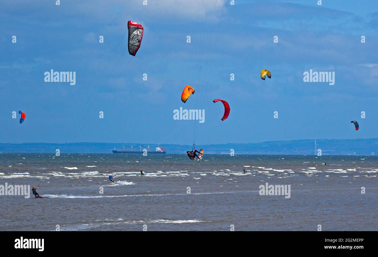 Longniddry, East Lothian, Scozia, Regno Unito. 12 giugno 2021. Vento 24 km/h potenziali raffiche 35 km/h con sole e nuvole che sembrava essere il tempo perfetto per più di 20 Kite Surfers che hanno dimostrato le loro abilità sul Firth of Forth. Foto Stock