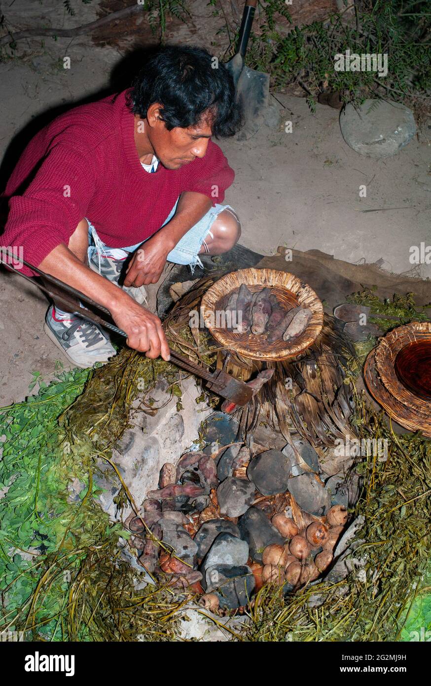 Nazca, Perù - Luglio 19 2010: Cena tradizionale Pachamanca preparata da un uomo indignato di notte cucinando a terra. Foto Stock