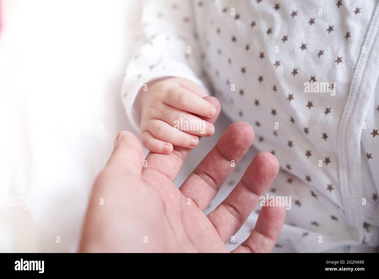 La mano delle madri che tiene la mano del bambino. Il bambino ha un mese. Carino mano piccola con le dita piccole. Concetto di amore e di cura di fondo. Foto di alta qualità Foto Stock