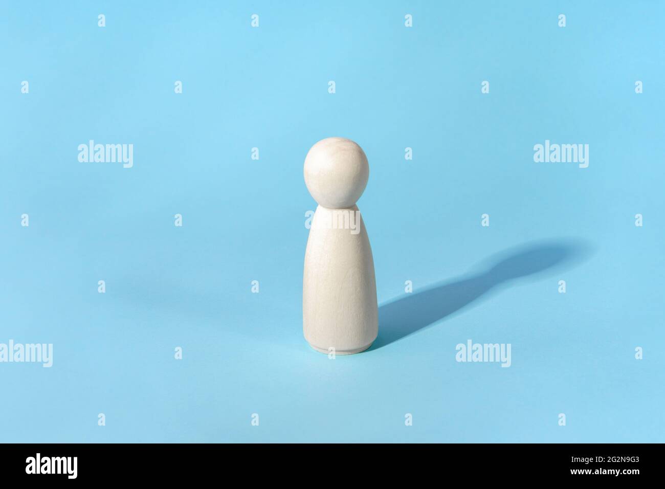 Concetto astratto della sola persona. Minimalista, figura in legno con ombra su blu Foto Stock