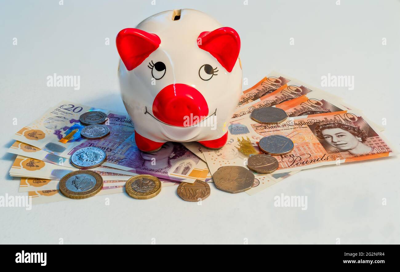 Piggy bank con banconote e contanti in sterlina britannica Foto Stock