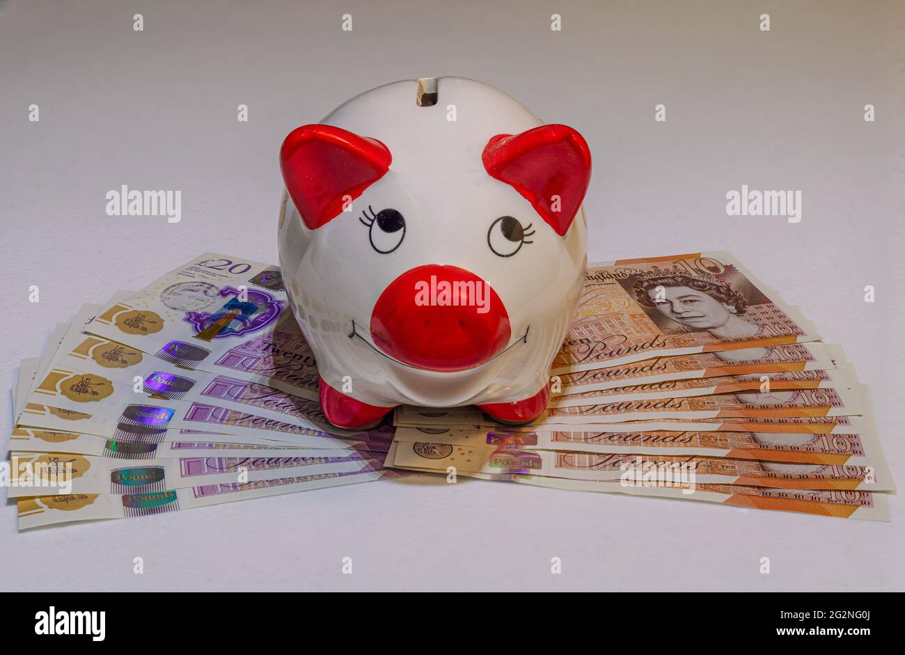 Piggy bank con banconote e contanti in sterlina britannica Foto Stock