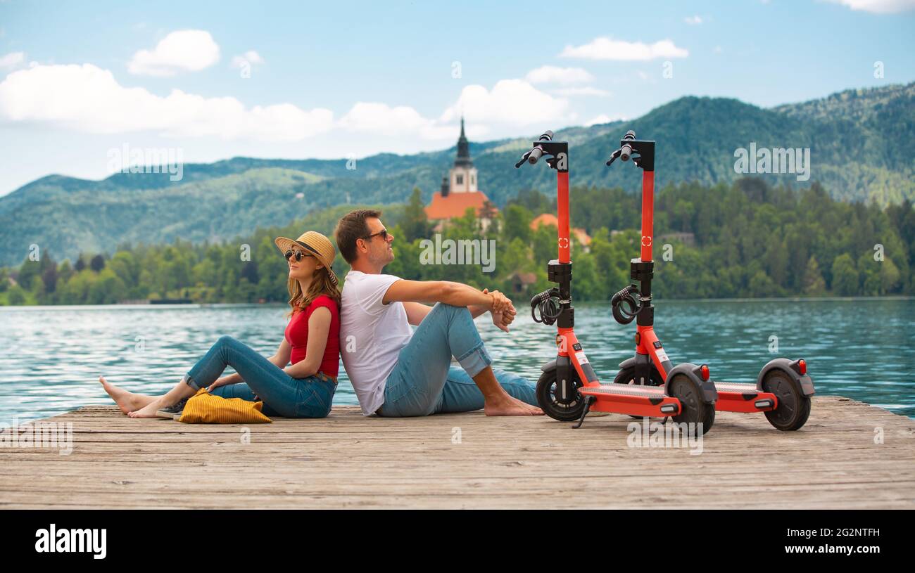 Giovane coppia che usa lo scooter elettrico come moderno mezzo di trasporto ecologico mentre esplora il verde paese Slovenia in vacanza. Energia ecologica verde Foto Stock