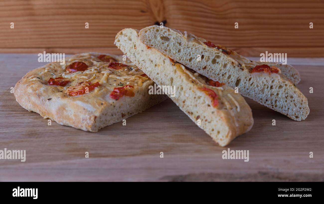 Pane italiano chiamato focacia ripieno con erbe di prosciutto di formaggio e pomodoro Foto Stock