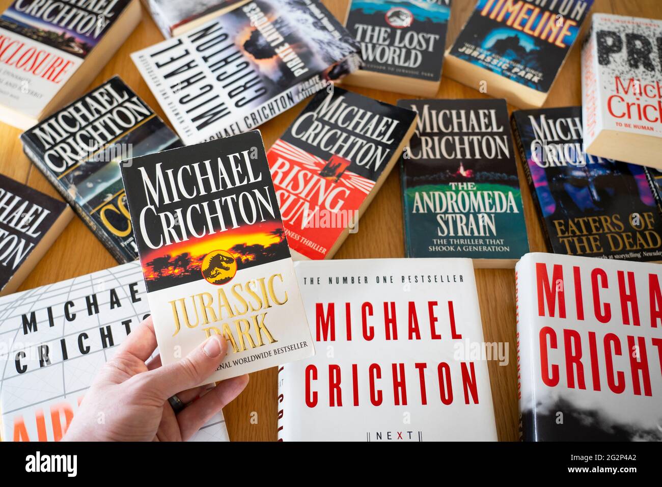 Una mano dell'uomo che tiene il libro Jurassic Park dell'autore americano  Michael Chrichton, con altri libri di Michael Crichton sullo sfondo Foto  stock - Alamy