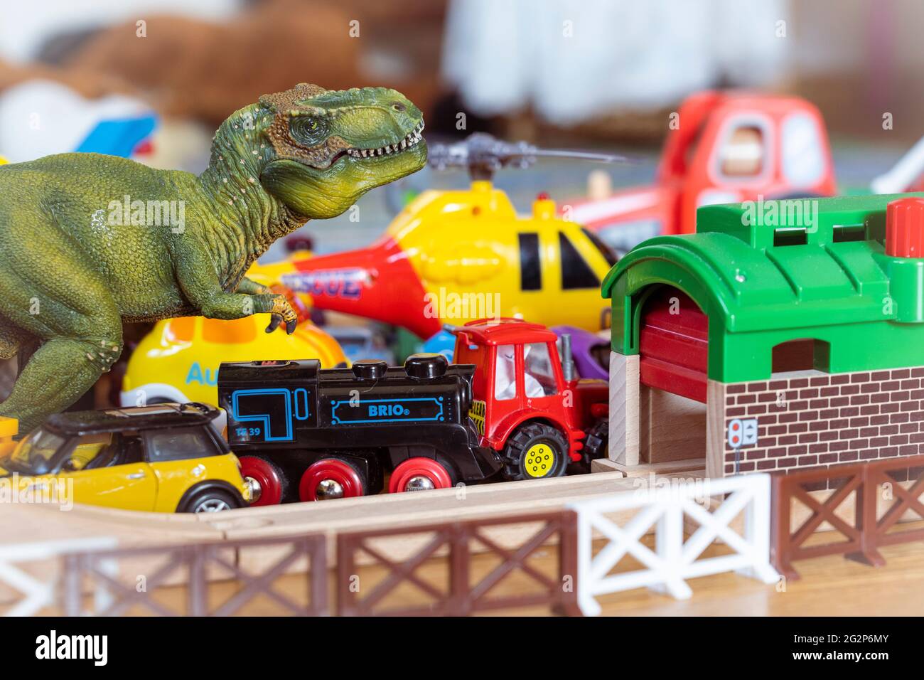 Re dei giocattoli - un giocattolo Tyrannosaurus rex si avea su un mix di treni giocattolo, trattori giocattolo e un elicottero Foto Stock