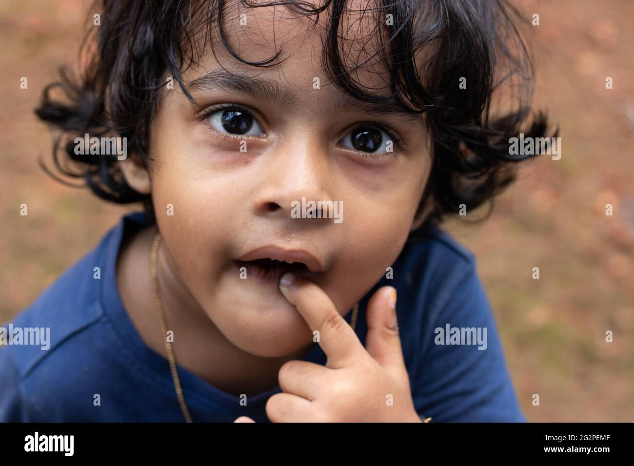 Primo piano di una bambina carina che fissava la fotocamera con curiosità Foto Stock