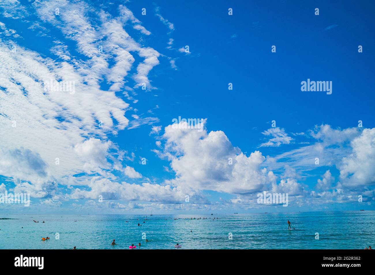 Oahu Hawaii persone godere Waikiki in acque turchesi contro cielo e nuvole Foto Stock