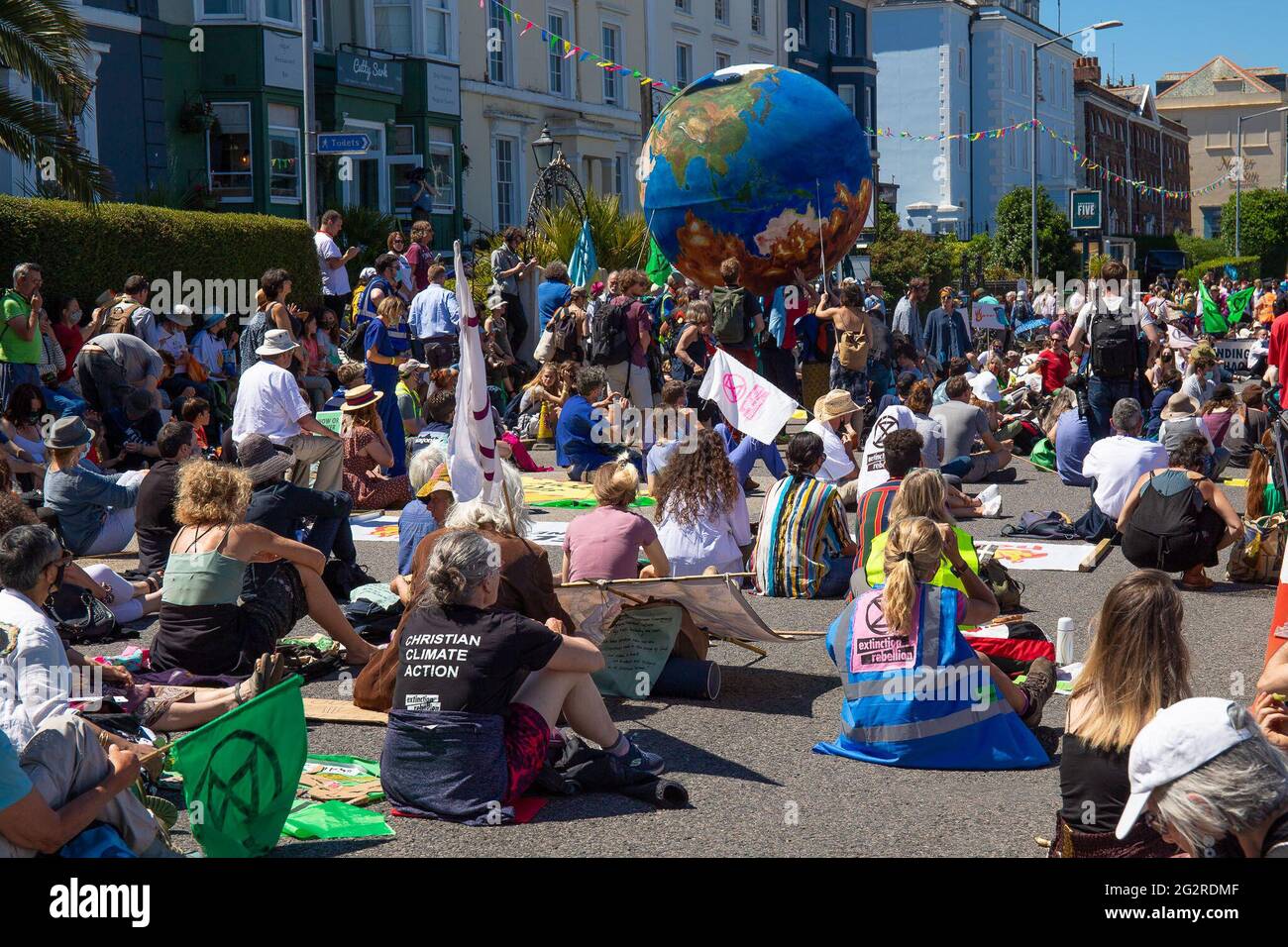 Falmouth, Cornovaglia, Regno Unito 12 giugno 2021 la ribellione per l’estinzione marciò in protesta contro le politiche di ‘lavaggio delle greenwashing’ del governo e degli affari al vertice del G7. I ribelli rossi guidano la marcia attraverso il centro città unendosi ai medici di XR e scrubber sporchi, terminando al centro di media. Foto Stock