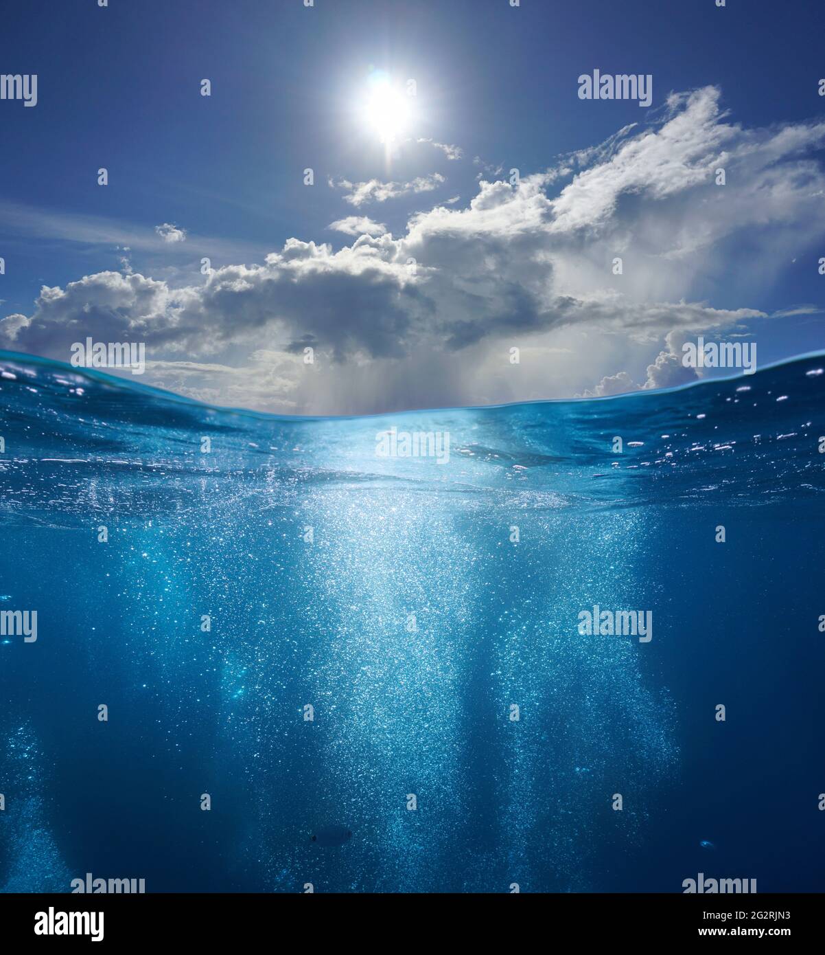 Mare marino, bolle d'aria mare sottomarino e cielo azzurro soleggiato con nuvole, vista divisa sopra e sotto la superficie dell'acqua Foto Stock